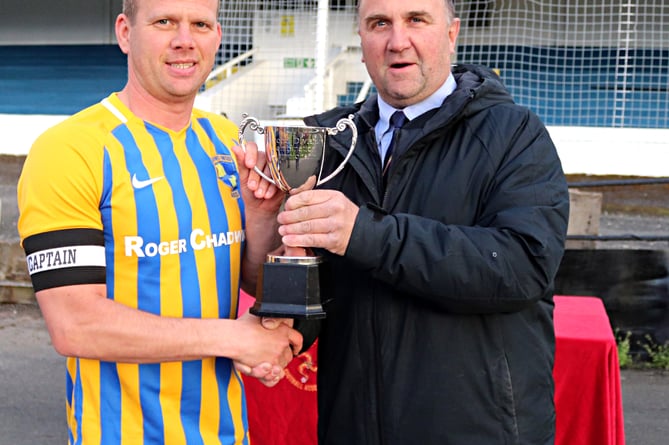 St John’s captain Wes Kitching receives the Combination Two trophy from Isle of Man FA president Tony Mepham (Photo: Paul Hatton)