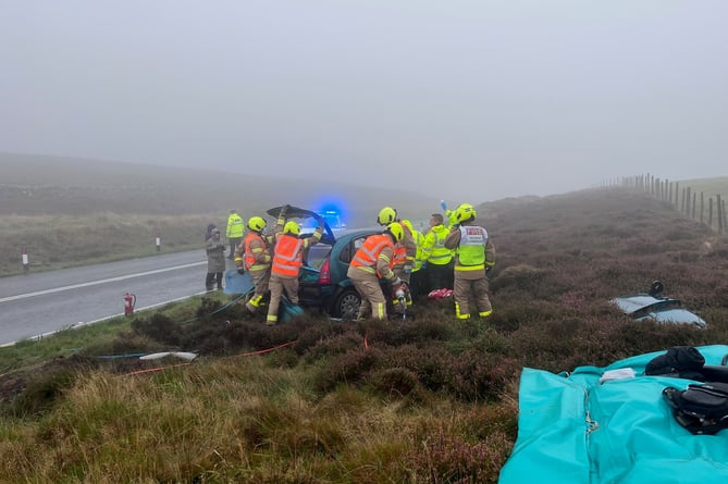 Emergency services work to free a motorist from a car on the Mountain Road this morning