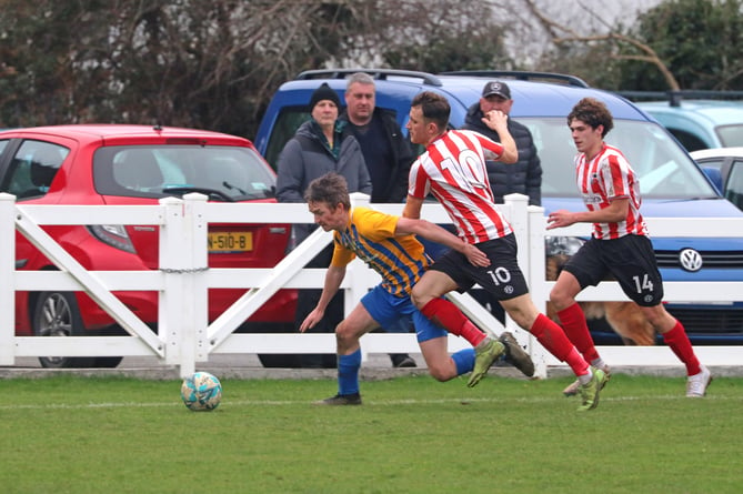 St John's United's Harry Rothwell looks to escape from Peel's Rhys Oates and Israel Dunn 