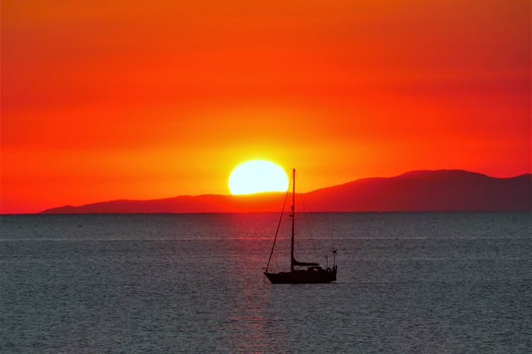 Sailing boat and the rising sun in Ramsey Bay