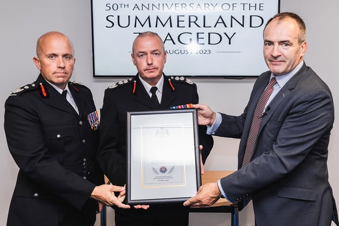 Chief Minister Alfred Cannan MHK presents the Scroll of Recognition to Deputy Chief Fire Officer John Murtagh, left, and Chief Fire Officer Mark Christian