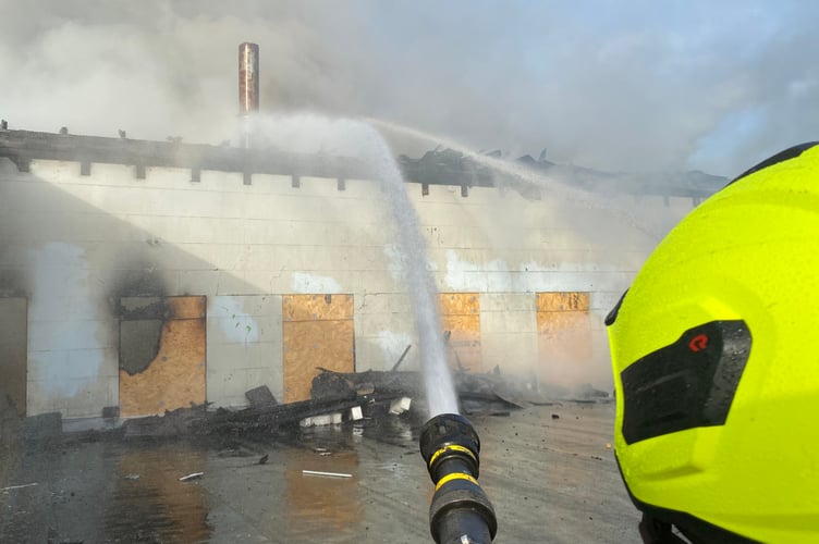 Firefighters hose down the rear of the building on Woodbourne Road