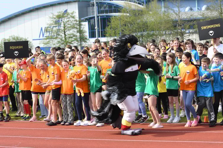 Manx Youth Games mascot Odin The Raven high fives youngsters taking part