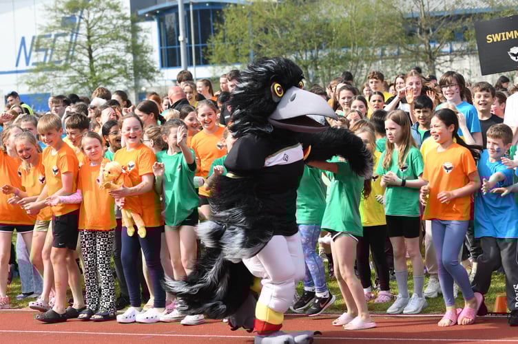 Manx Youth Games mascot Odin The Raven high fives youngsters taking part