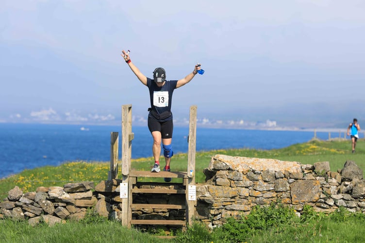 Arms aloft as a runner climbs a stile at Scarlett