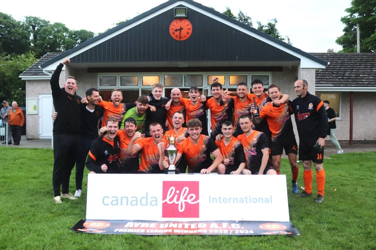 Ayre United players and coaches celebrate with the Canada Life Premier League trophy after sealing the championship with a 3-1 victory over St Mary's in their last game of the season on Friday evening