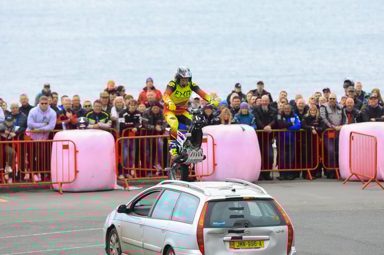 Steve Colley rides over an old banger during his performance at Peel TT Day