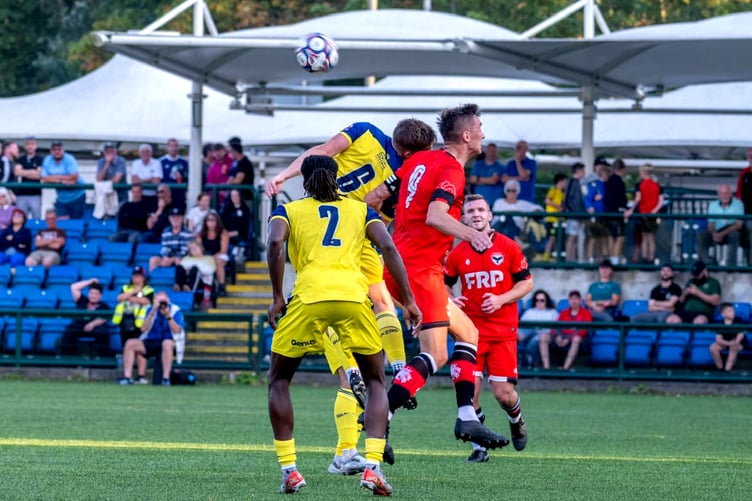 FC Isle of Man captain Sean Doyle and a Bury opponent challenge for an aerial ball during Saturday evening's dramatic NWCFL Premier Division clash at the Bowl. Doyle opened the scoring for the Ravens, only for the visitors to snatch a 95th-minute equaliser (Photo: Hannah McHugh)