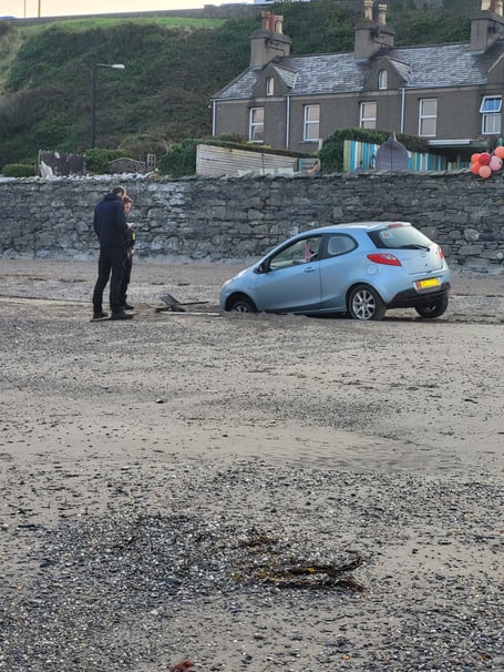 Police officer inspects stranded hatchback