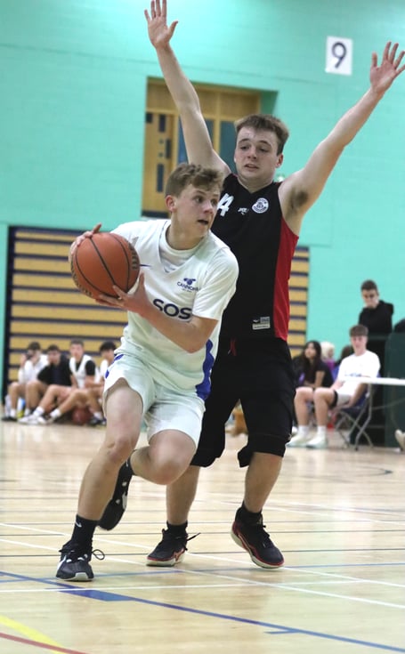 SOS Cannons' Rowan Coulter drives past the defence of Ravens' Zak Mitchell during Thursday evening's opening night of the 2024-25 Isle of Man basketball season (Photo: Martin Dunne)