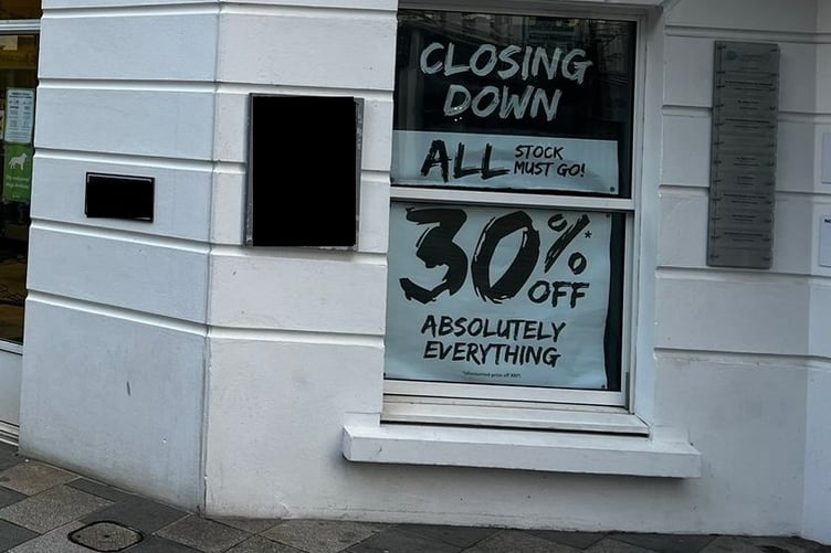 A 'closing down' sign in the window of Millets on Strand Street, Douglas
