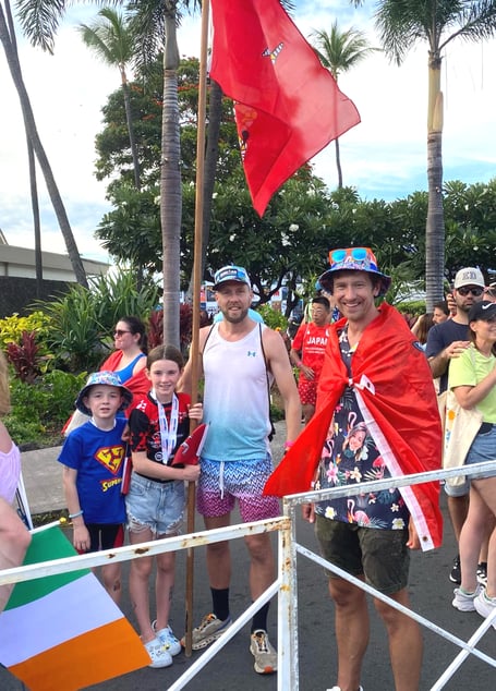 Isle of Man athletes Dr Richard Callow (right) and Nigel Quaye with his children Bella and Austin flying the Manx flag at the 2024 Ironman World Championship in Hawaii 