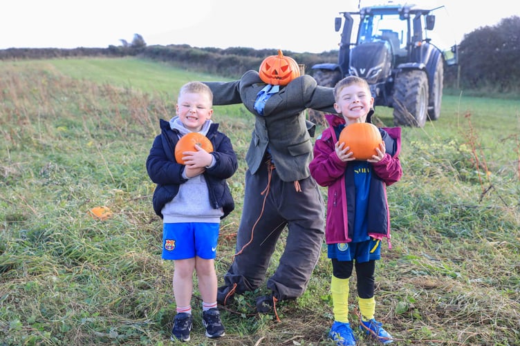 Connor and Oliver French next to a spooky pumpkin scarecrow