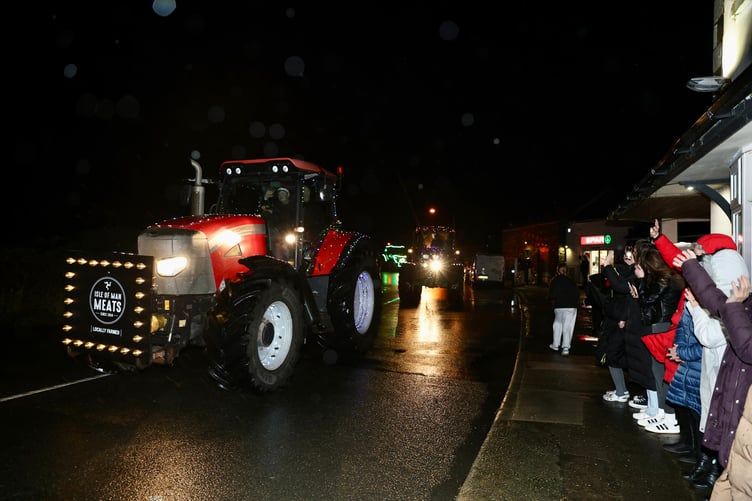 Manx Meats' Christmas tractor goes past the Colby Glen and a number of waving spectators