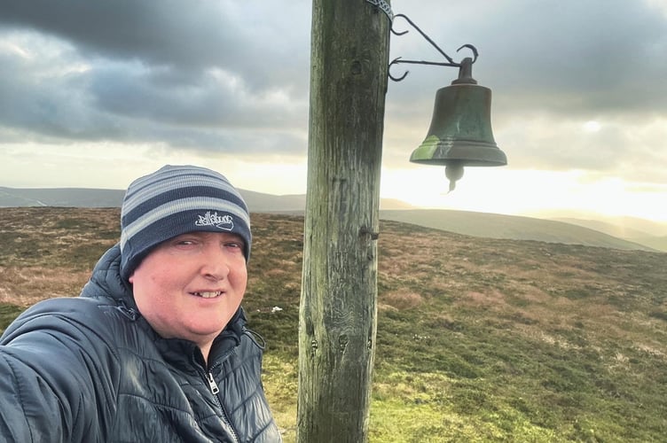 Reporter James Campbell ringing the bell at the top of Slieu Freoaghane