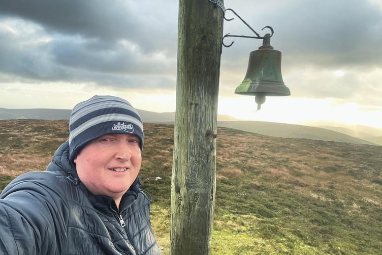 Reporter James Campbell ringing the bell at the top of Slieu Freoaghane