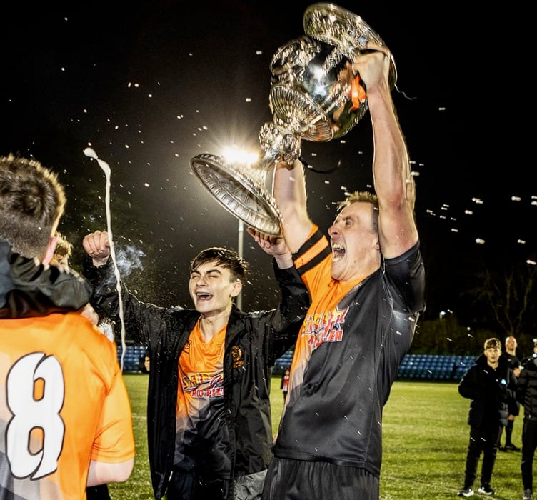 The Champagne flows as Ayre United captain Jamie Callister triumphantly hoists the Plum Properties Railway Cup above his head after the Tangerines beat Peel in the Boxing Day final at the Bowl (Photo: Gary Weightman)