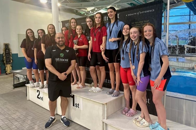 Island swimming coach Lee Holland with (left to right) QEII's Beth Christian, Charlotte Walker, Lauren Dennett and Olivia Williamson, the St Ninian's quartet of Holly McEvoy, Hailey Henrico, Molly Bevan and Chloe Batty, plus Castle Rushen's Libby Curphey, Kaya Reynolds, Holly Wilson and Jorja Hedley