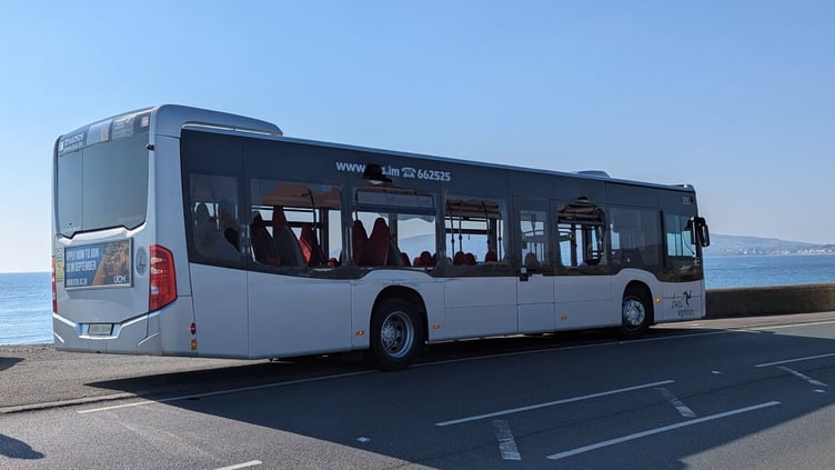 The side of a single-decker bus with several smashed windows