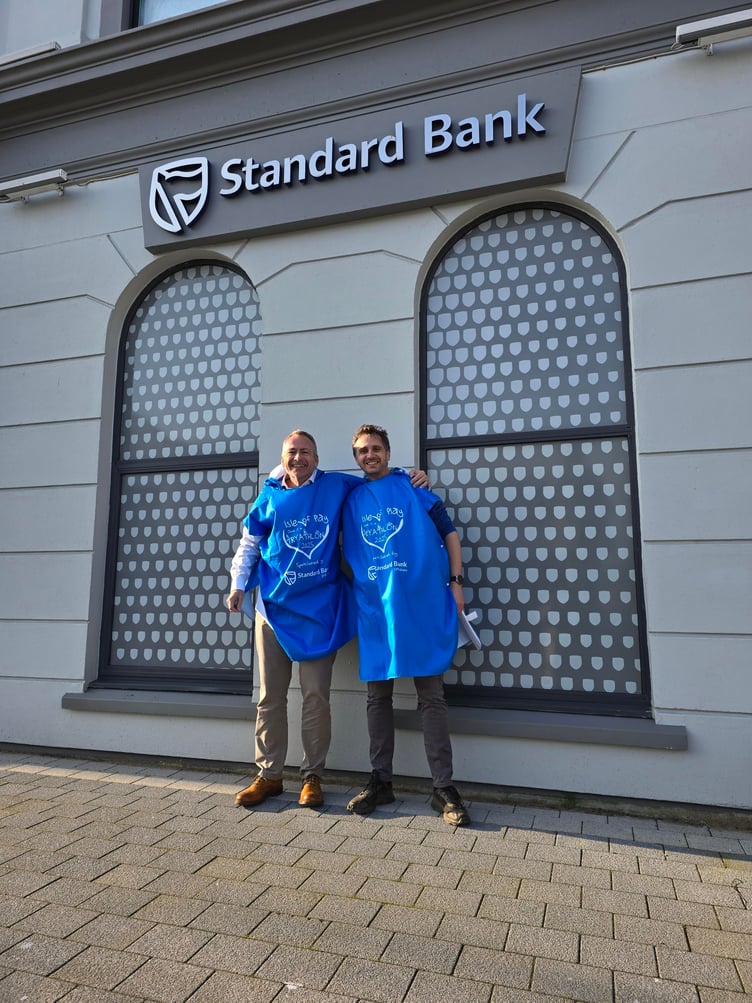 Stand Bank Offshore's Lee Francis with Isle of Play's Chris Gregory (right) and the event's 'I Gave it a Try-Athlon' poncho towel