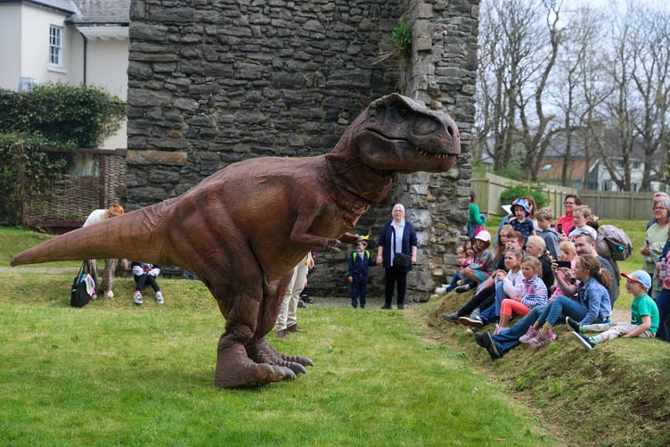 Children look on in awe at a large dinosaur