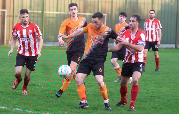 Ayre United midfielder Declan Cummins attempts to hold off the attentions of Peel caption Matt Woods during Tuesday evening's Hospital Cup quarter-final at Douglas Road. Woods helped his side win 2-1 (Photo: Paul Hatton)
