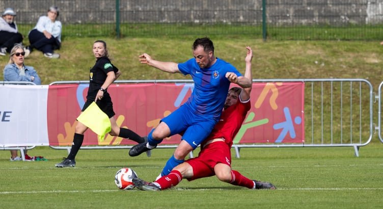 The Isle of Man's Harry Best is challenged by an Ynys Mon opponent during the two sides' semi-final at the Island Games on Thursday evening (Photo: Gary Weightman)