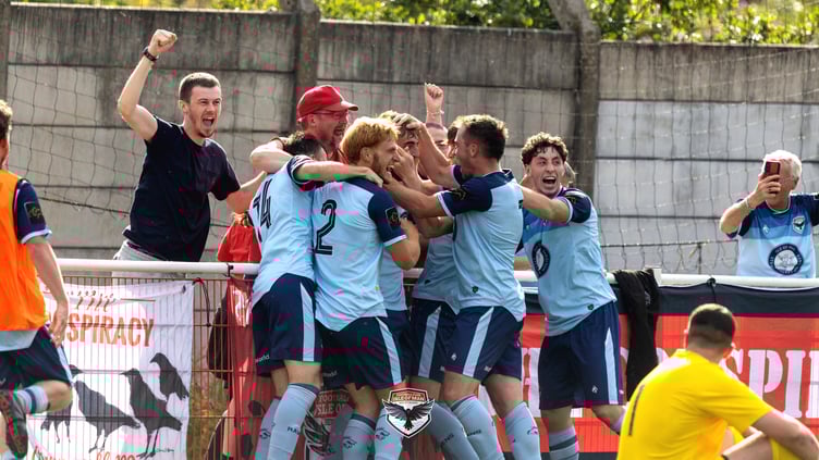Joe Middleton is mobbed by his FC Isle of Man team-mates and fans after netting a dramatic injury-time winner against Abbey Hey on Saturday afternoon (Photo: Hannah McHugh)