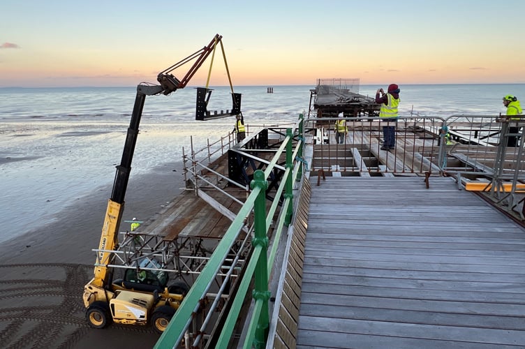 Cross beam is lifted into position as sun sets on Queen's Pier