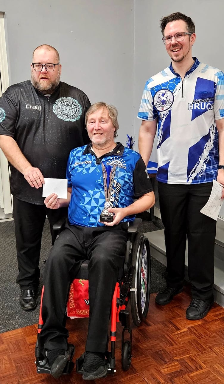 Isle of Man wheelchair darter Darren Kennish celebrates with his trophy alongside Scottish darters Craig Robertson (left) and Grant Murray