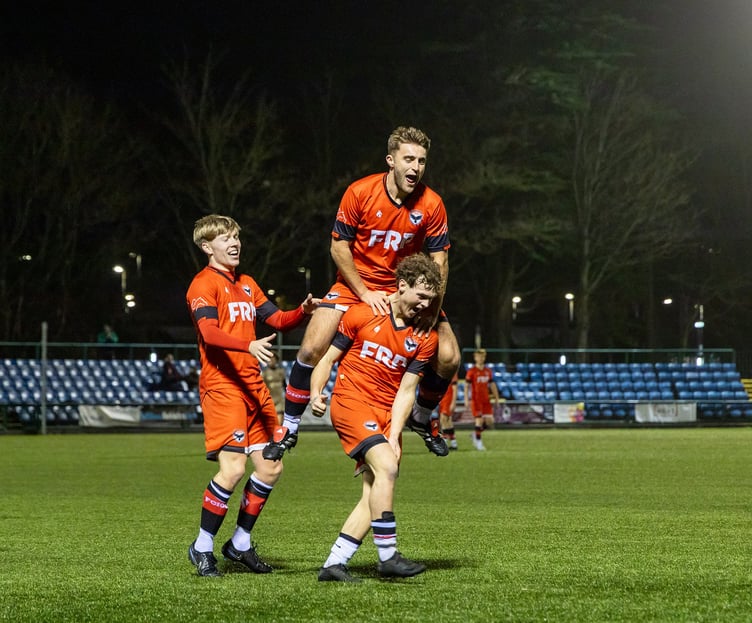 An airborne Joe Middleton and Kyle Watson (left) celebrate with Dean Pinnington after his goal against AFC Liverpool at the Bowl on Saturday evening (Photo: Hannah McHugh)