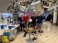 Friends cycle for 24 hours on exercise bike at shopping centre