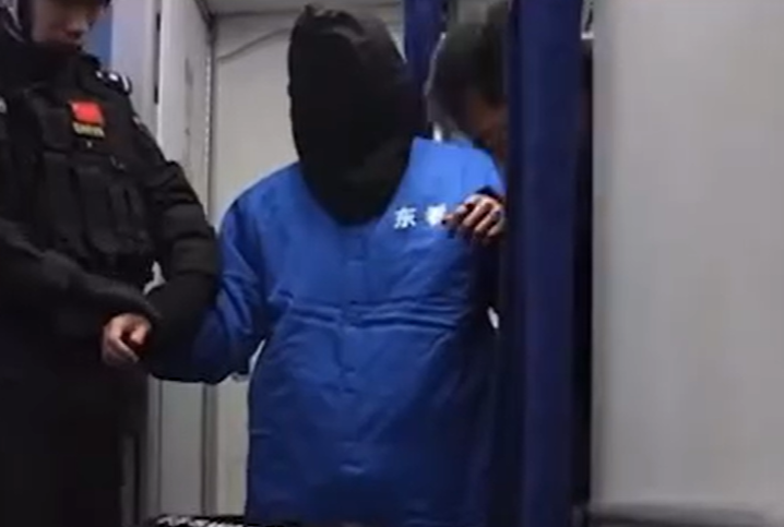 Chen Zhi is hooded before being escorted off the aircraft at Beijing