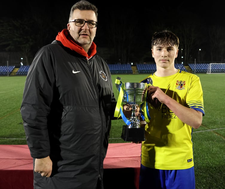 Onchan captain Preston Cleator receives the Under-18s FA Cup from Isle of Man FA football development manager Simon Elson following Wednesday evening's final at the Bowl (Photo: Paul Hatton)