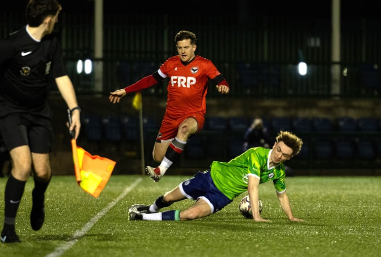 FC Isle of Man winger Ste Whitley hurdles a challenge from a Chadderton opponent during Saturday's evening's Premier Division match at the Bowl (Photo: Hannah McHugh)