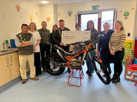 Tom hands a cheque for £6,000 to children's ward