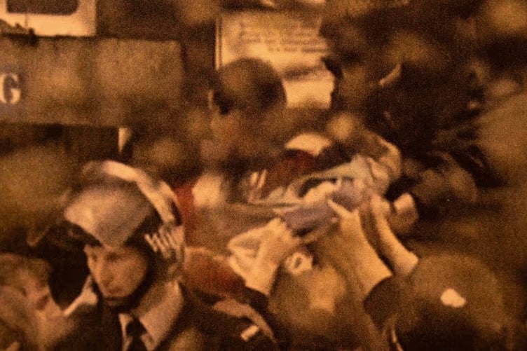 A still from TV footage showing Graeme being passed over a wall by Liverpool supporters at Hillsborough stadium