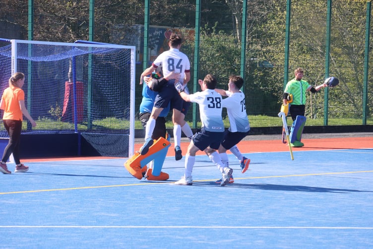 Bacchas' goalkeeper Dominic Howard is mobbed by team-mates Alex Stewart (84), Will Wiseman (hidden), Elliot Reid (38) and Nick Wilson (75) after making the decisive penalty save in Saturday's Men's Cup final (Photo: Paul Hatton)