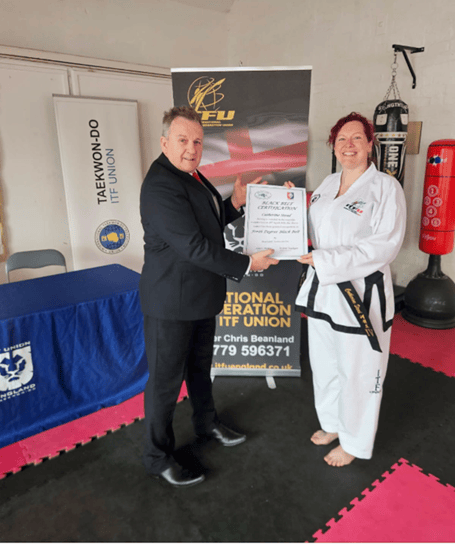 Catherine Stead receiving her black belt certification from ITF Union England and Isle of Man president Chris Beanland