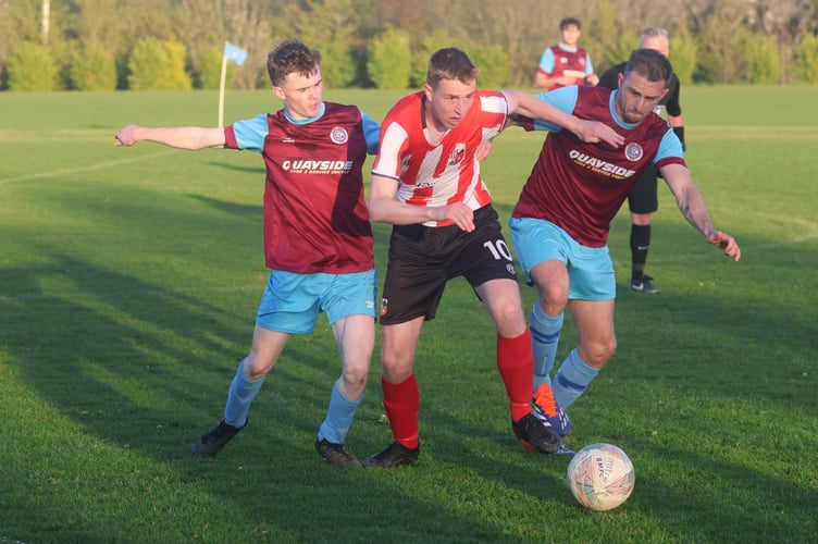 Peel's Jason Charmer tries to wriggle clear of the Union Mills defence during Tuesday evening's Premier League match at Garey Mooar (Photo: Paul Hatton)