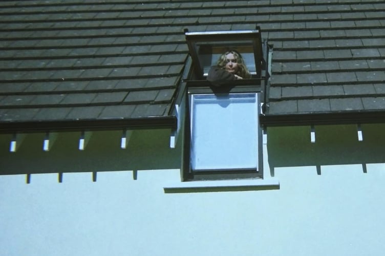 Artist Annabel Lauren pictured looking out of her Velux window in her childhood home, with Velux being the name of her debut album