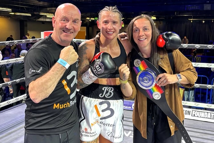 Jade Burden celebrates in the ring with her Commonwealth belt alongside coach Peter Roberts Jr and Leonie Harrison