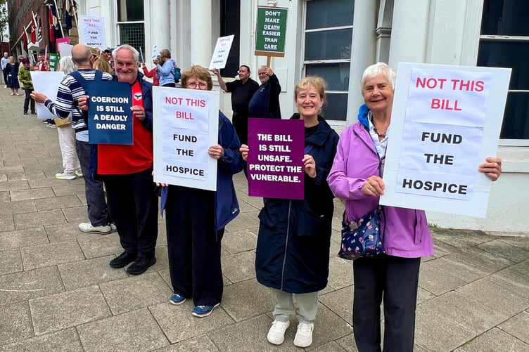 Opponents of the Assisted Dying Bill hold placards outside the Tynwald building