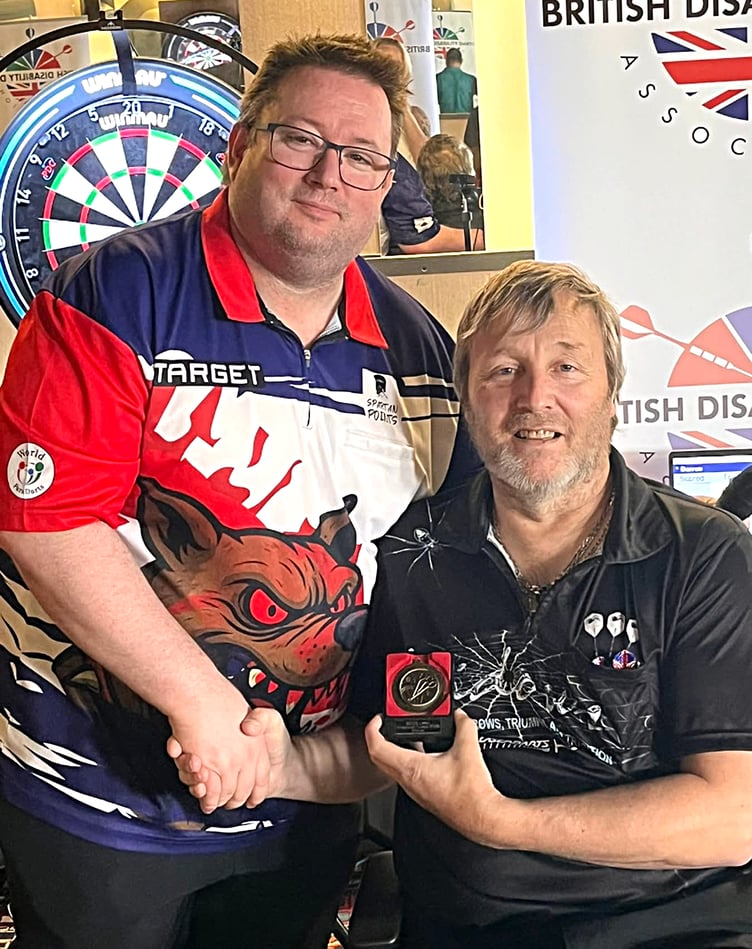 Isle of Man wheelchair darter Darren Kennish receives his Lakes Open medal from British Disability Darts Association tournament director Matt Doe