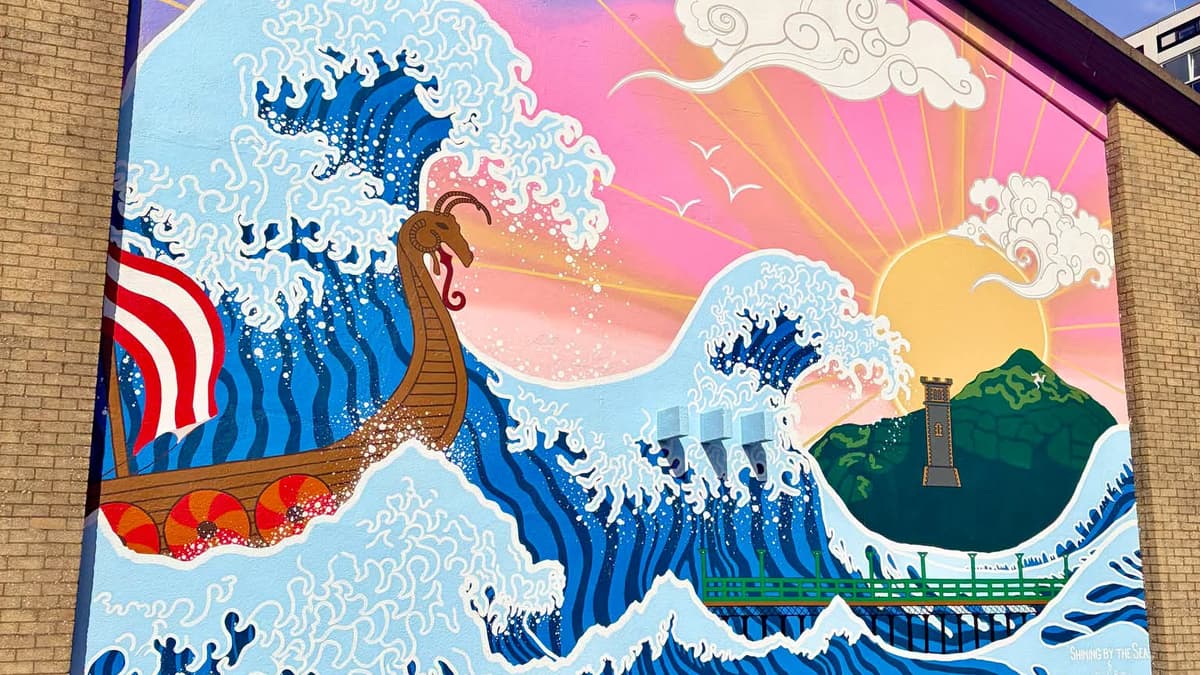 A vibrant mural featuring a Viking ship amidst large waves and a setting sun