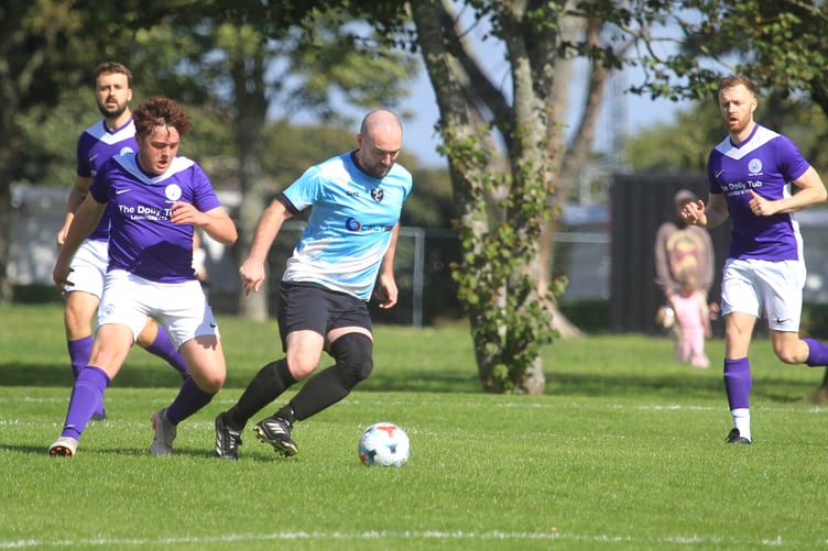 Gymns/DAFC captain Daniel Kewley looks to escape the attentions of Douglas and District's Nathan Perager on the new pitch at Noble's Park (Photo: Dave Norton)