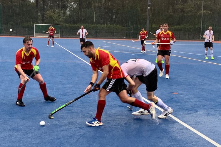 The Isle of Man's Tom Tsitsos holds off a challenge from a Bowdon player in torrential conditions at the NSC on Saturday (Photo: Rachel Andrew)