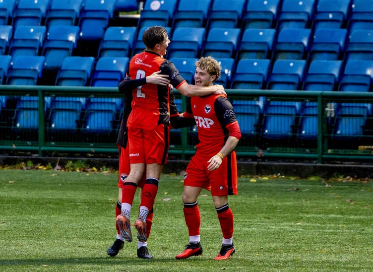 Jason Charmer (hidden) is mobbed by team-mates Jack Higgins (left) and Dean Pinnington after scoring a late winner for FC Isle of Man against Maghull on Saturday afternoon (Photo: Hannah McHugh)
